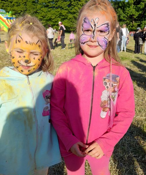 Dwie dziewczynki z pomalowanymi na twarzy motylem i tygrysem